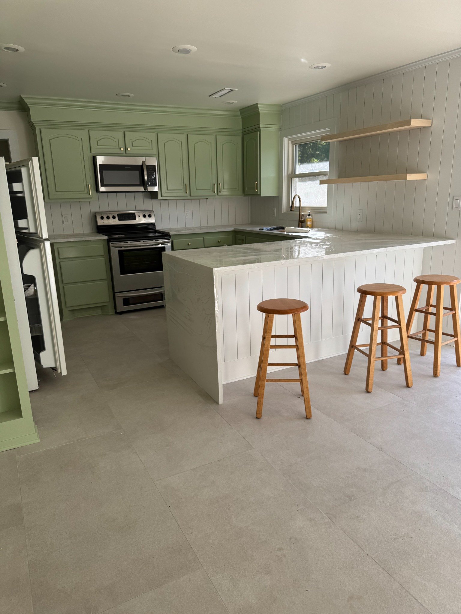 Green and white remodeled kitchen with large tile flooring